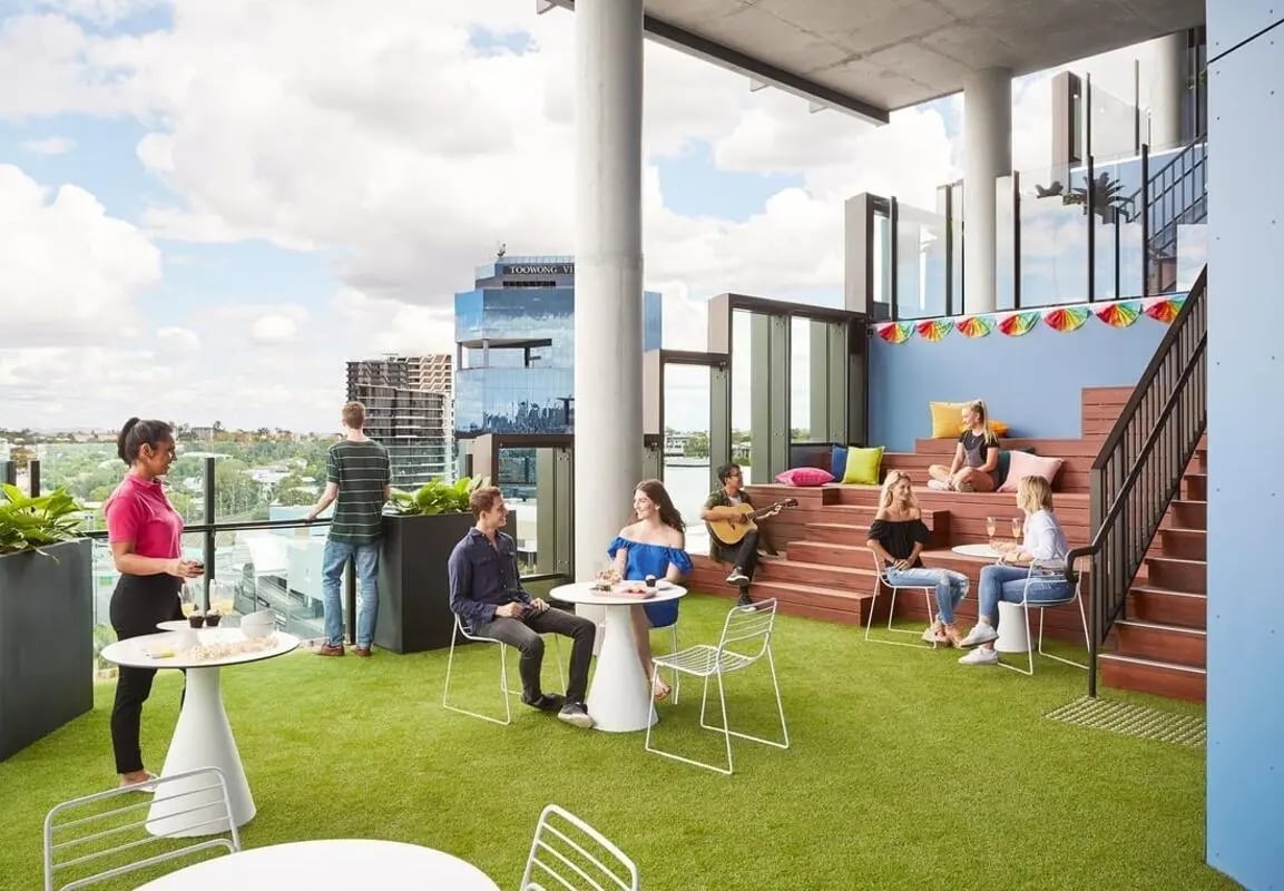 People relaxing on a rooftop lounge area. at Scape Toowong in Brisbane Student Accommodation