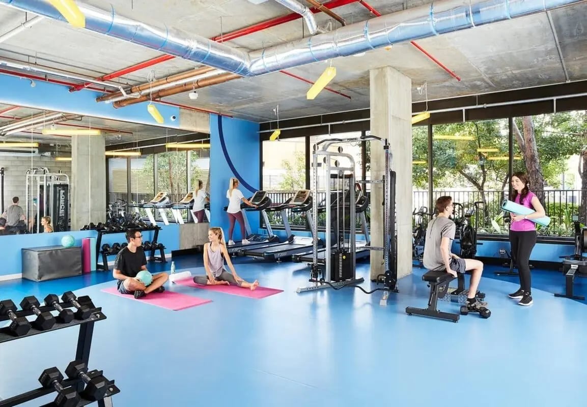 Gym with treadmills weights and people working out fitness room at Scape Toowong in Brisbane Student Accommodation