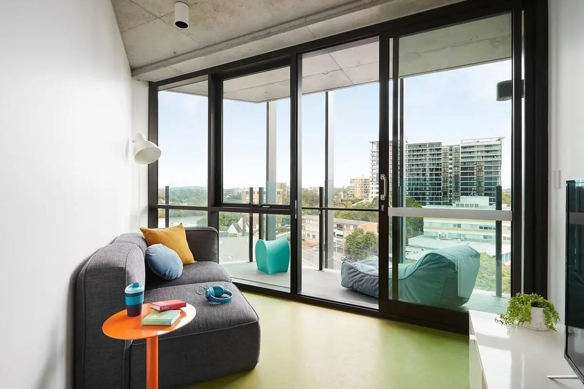 Grey sofa orange table headphones books living room at Scape Toowong in Brisbane Student Accommodation