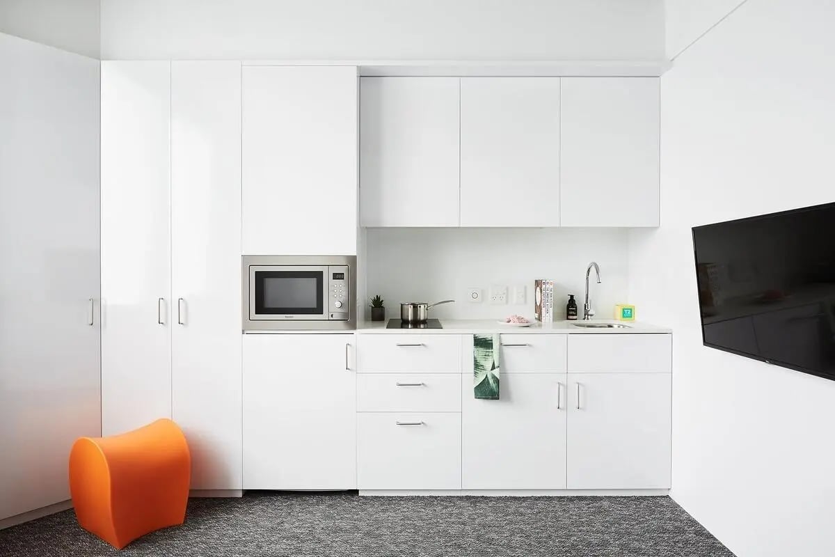 White kitchen cabinets microwave orange stool kitchen at Scape Toowong in Brisbane Student Accommodation