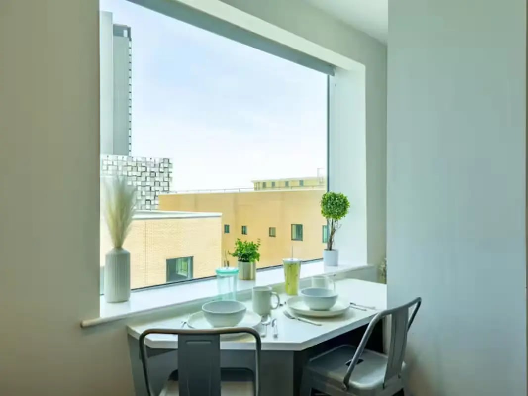 Table chairs place settings plants window dining area at Redvers Tower in Sheffield Student Accommodation