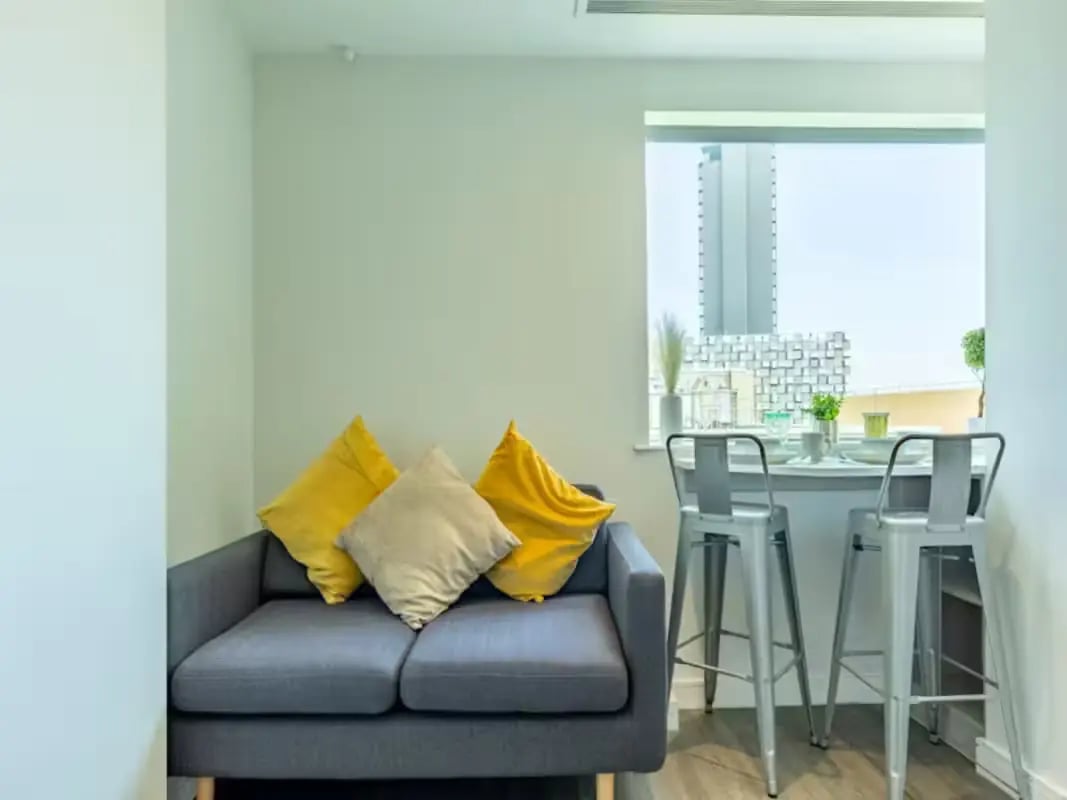 Sofa with yellow pillows kitchen dining area at Redvers Tower in Sheffield Student Accommodation