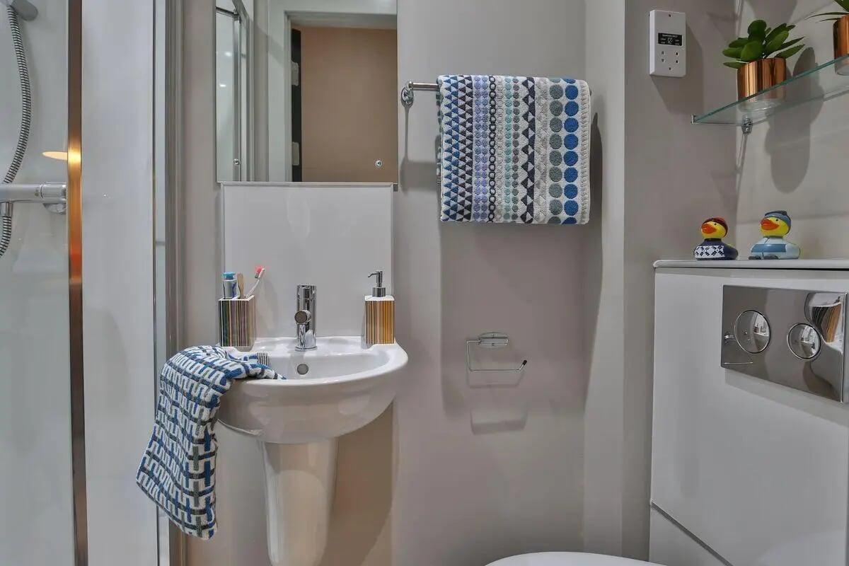 Sink toiletries towel rack toilet cistern bathroom at George Street Apartments in Glasgow Student Accommodation