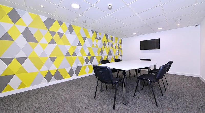 Table with chairs geometric wall TV common area at 88 Bromsgrove House in Birmingham Student Accommodation