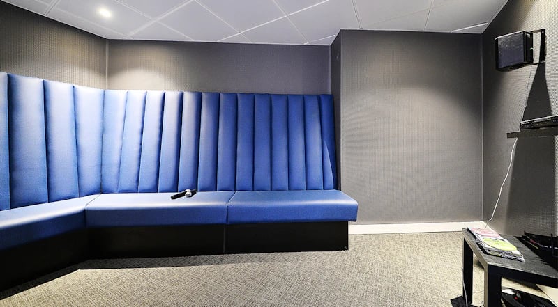 Blue booth seating with microphone and TV media console living area at 88 Bromsgrove House in Birmingham Student Accommodation