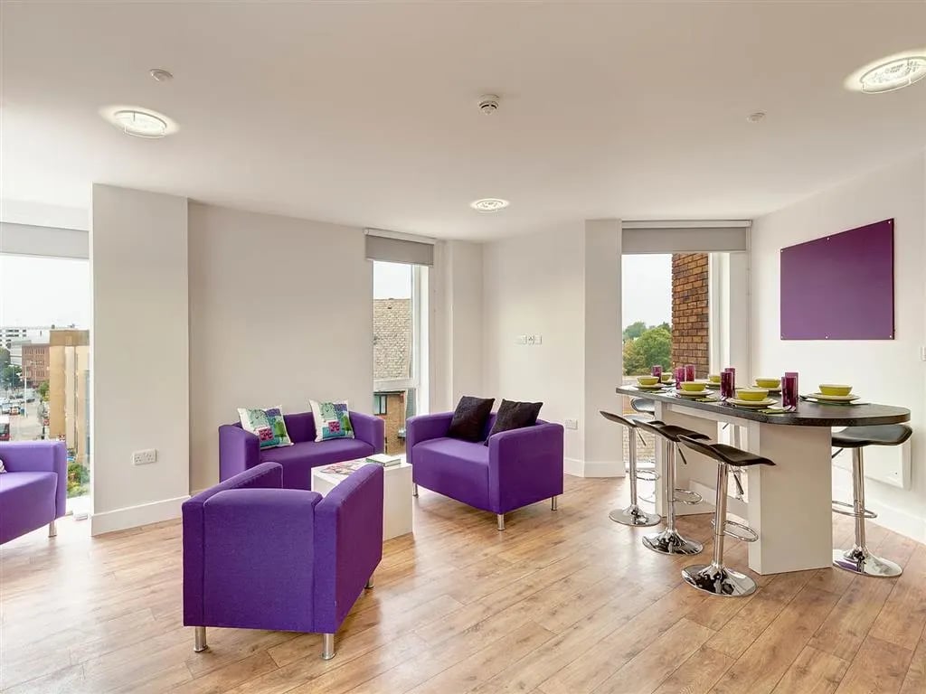 Purple sofas bar stools and dining table Living room at Davidson House in Kingston Upon Thames Student Accommodation