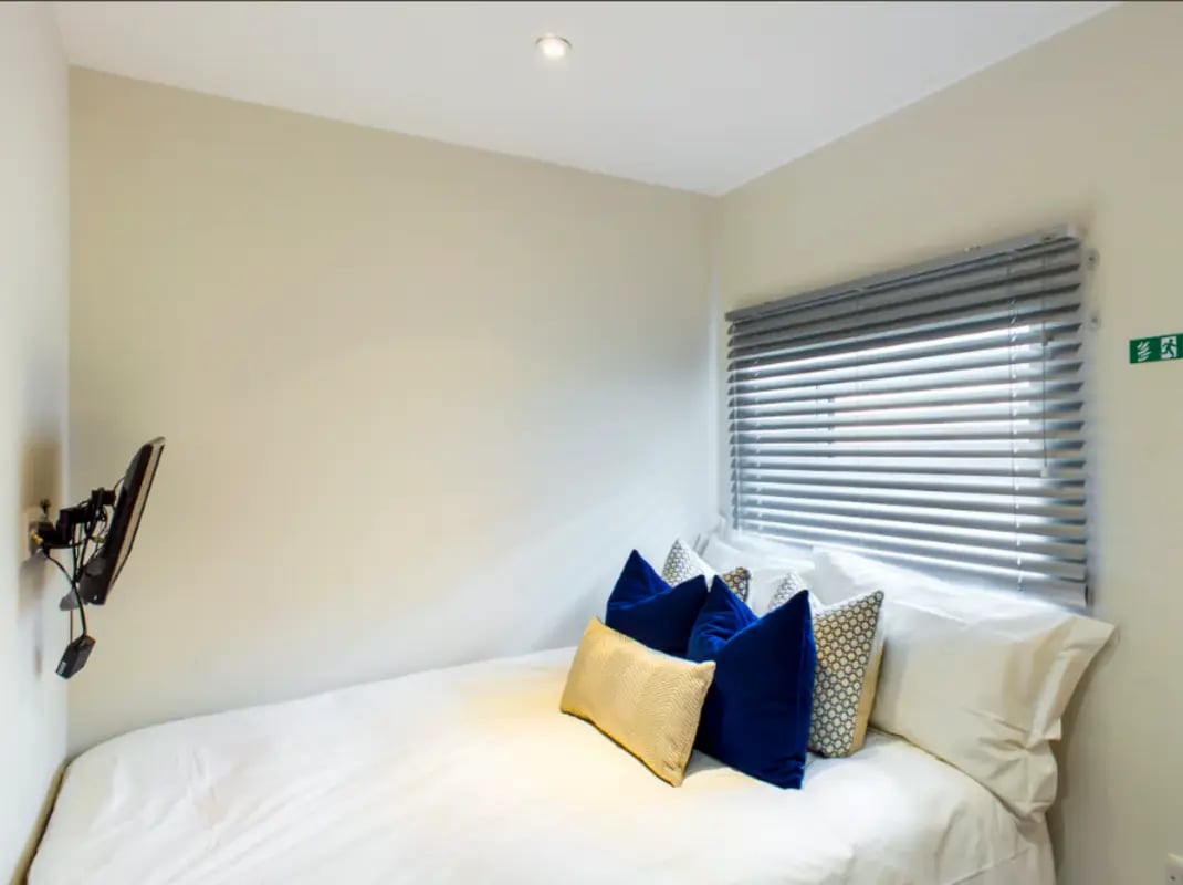 Bed with pillows TV on wall bedroom at 21 Queen Anne Street in Stoke-On-Trent Student Accommodation