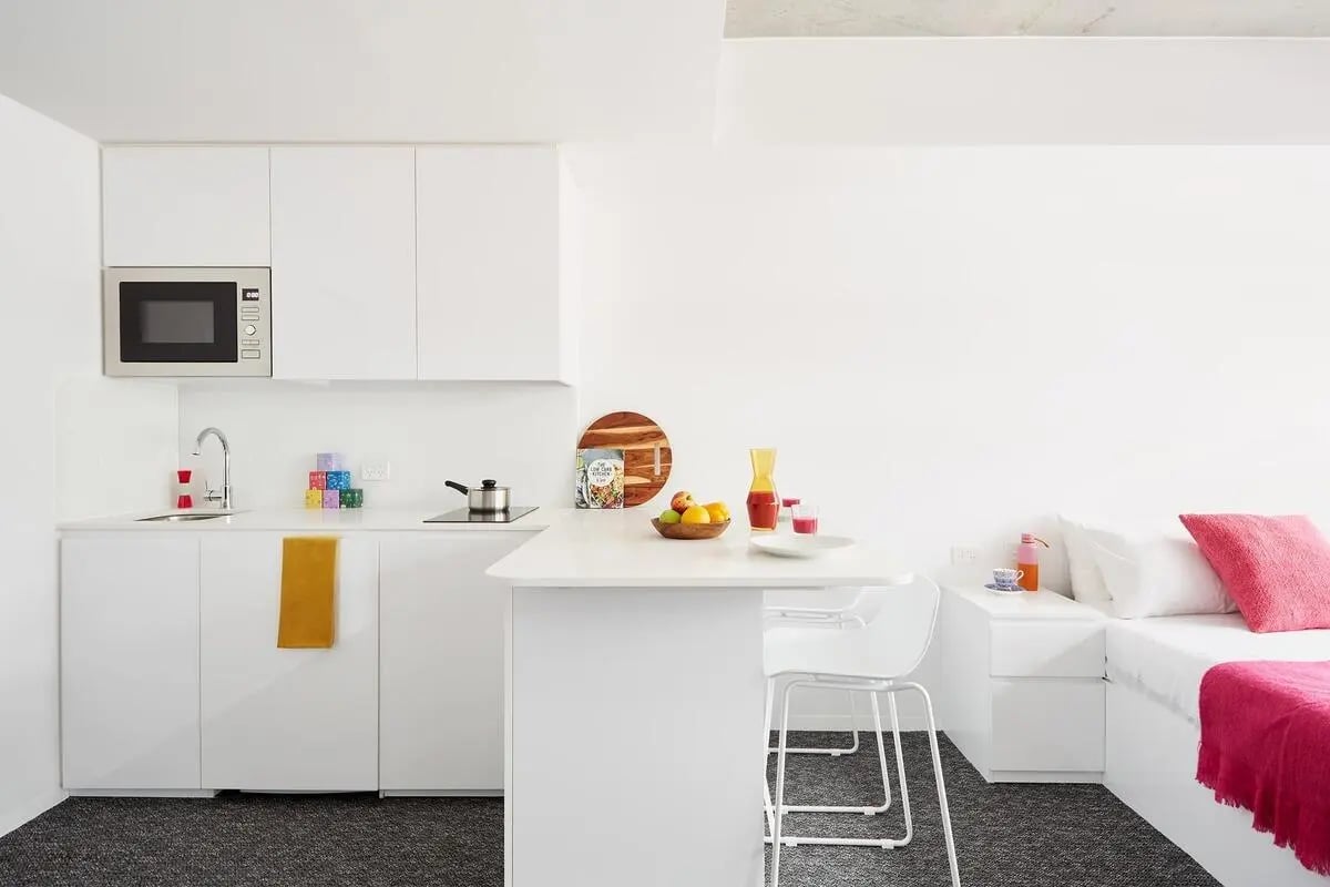 White kitchen counter microwave sink and bed at Scape Carlton in Melbourne Student Accommodation
