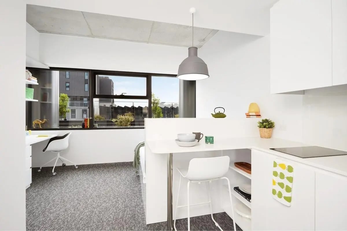 Desk chair bed kitchen bar stools and counter living room at Scape Carlton in Melbourne Student Accommodation
