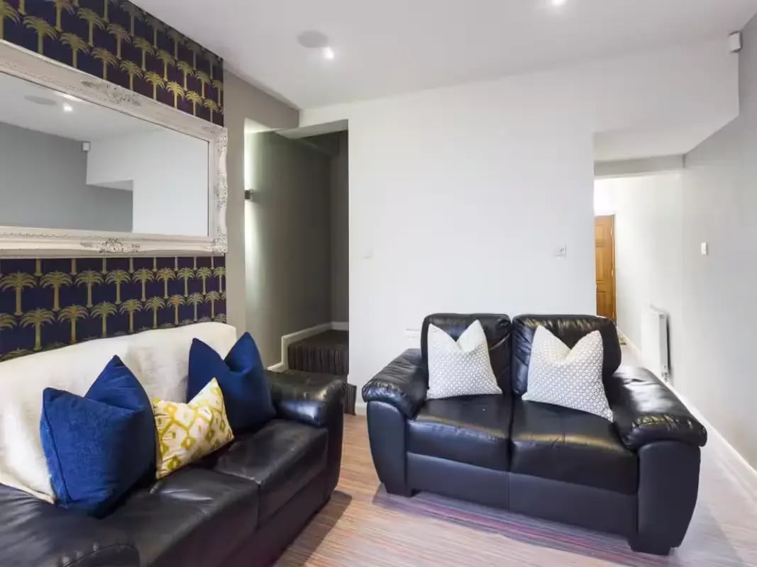 Black sofas with patterned pillows large mirror living room at 93 Thornton Road in Stoke-On-Trent Student Accommodation