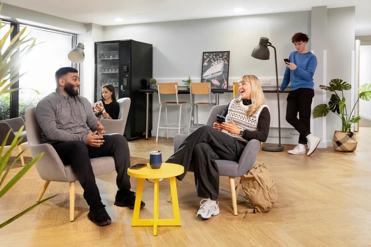 Students relaxing in armchairs near vending machine common area at Mary Sturge in Birmingham Student Accommodation