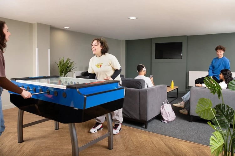 Foosball table, sofas, people playing and relaxing, common room at Mary Sturge in Birmingham Student Accommodation