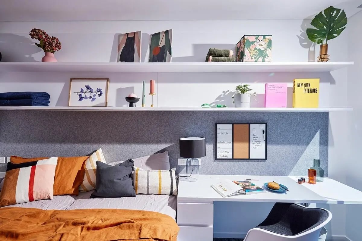 Bed with pillows desk and shelves bedroom at Scape Redfern in Sydney Student Accommodation
