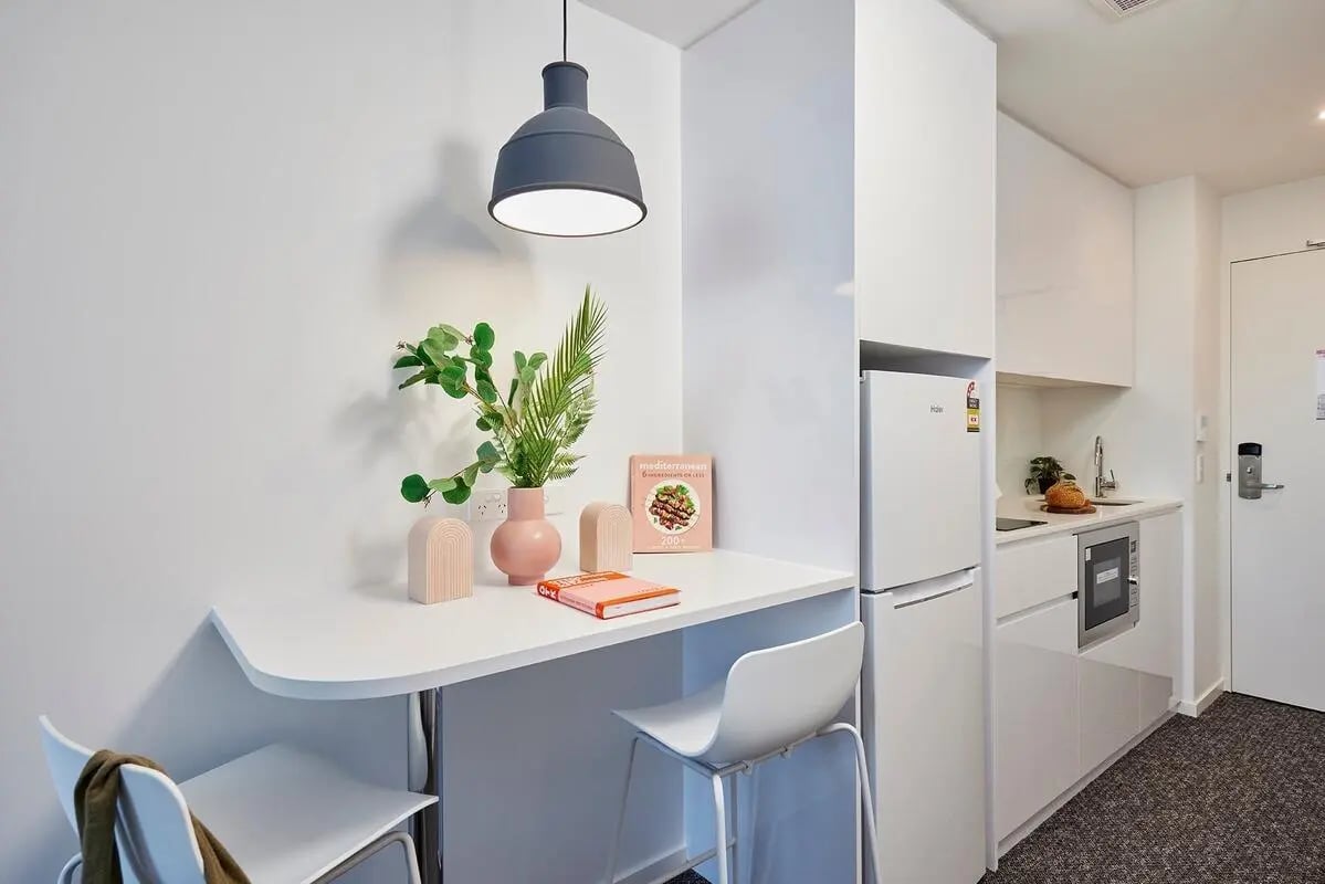 Table vase chairs fridge microwave kitchen area at Scape Redfern in Sydney Student Accommodation