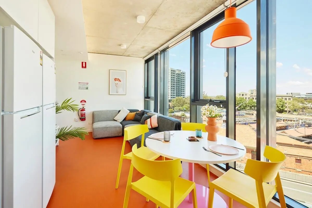 White refrigerators grey sofa yellow chairs dining table Living room at Scape Redfern in Sydney Student Accommodation