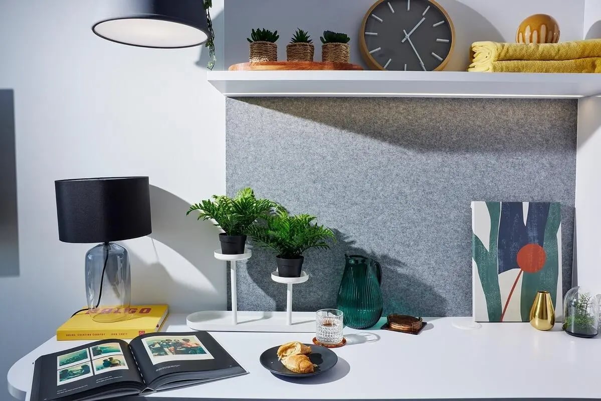 Desk with lamp plants book artwork and pastries study area at Scape Redfern in Sydney Student Accommodation