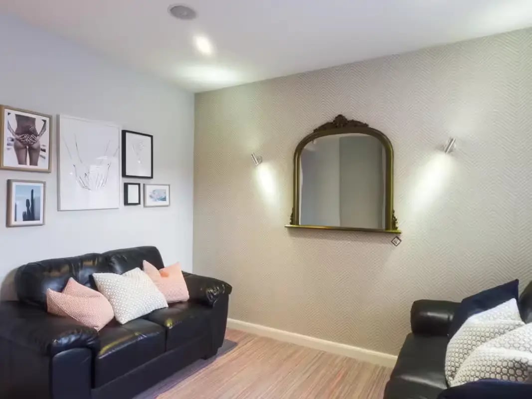 Black couches framed art mirror living room at 41 Crowther Street in Stoke-On-Trent Student Accommodation