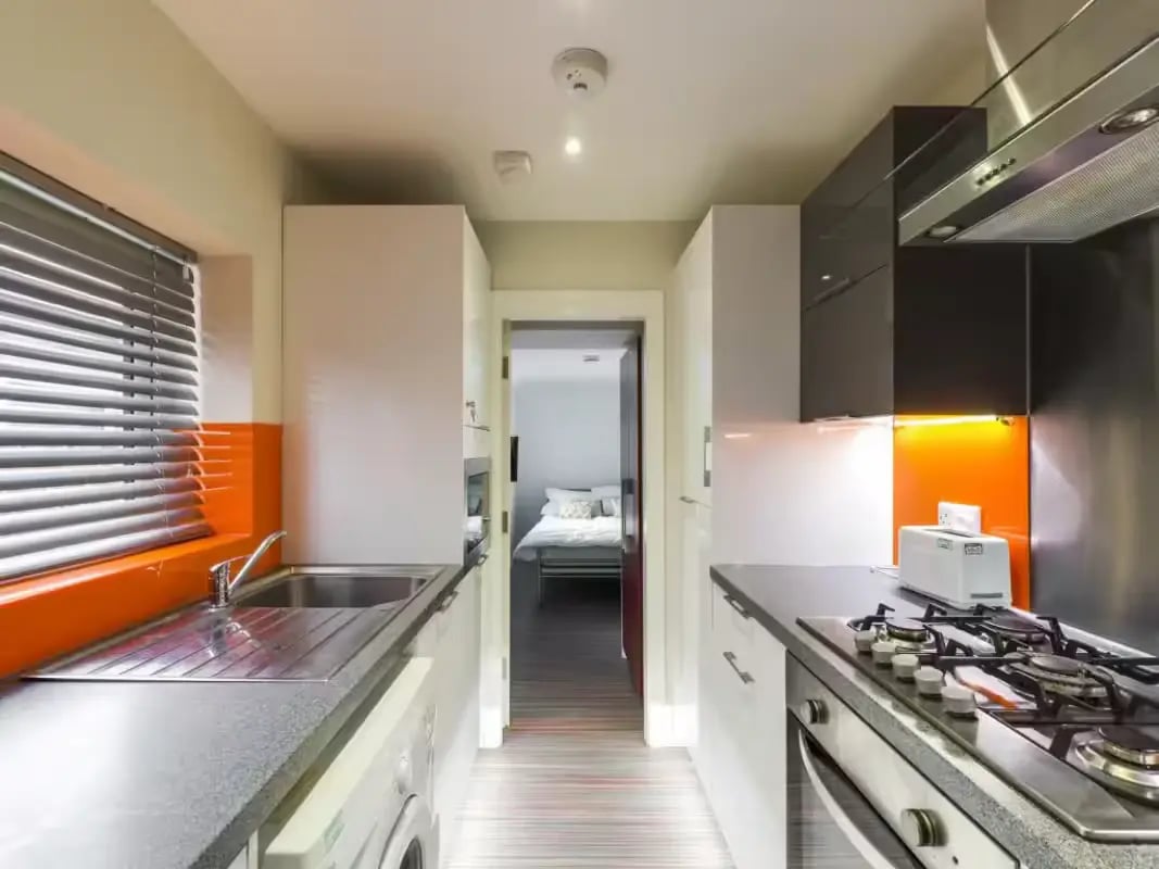 Compact kitchen with stove sink and bedroom beyond kitchen at 41 Crowther Street in Stoke-On-Trent Student Accommodation