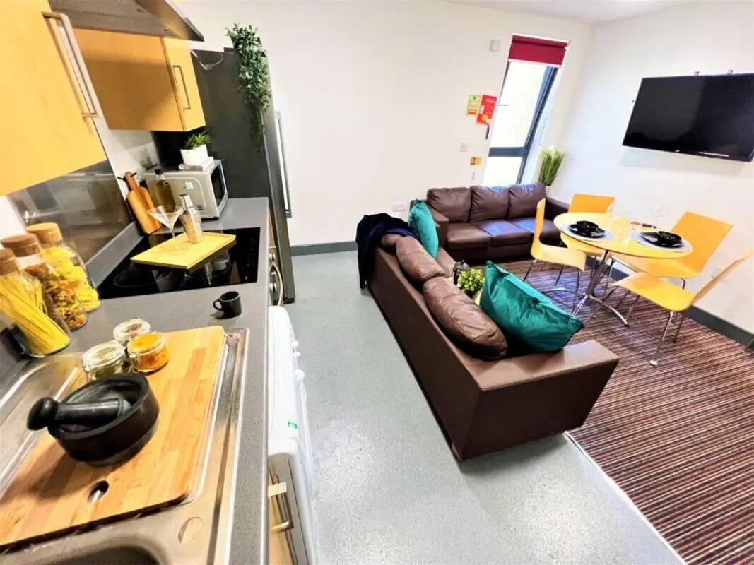 Kitchen with pasta jars sofas table chairs and TV living area at Parklane House in Sunderland Student Accommodation