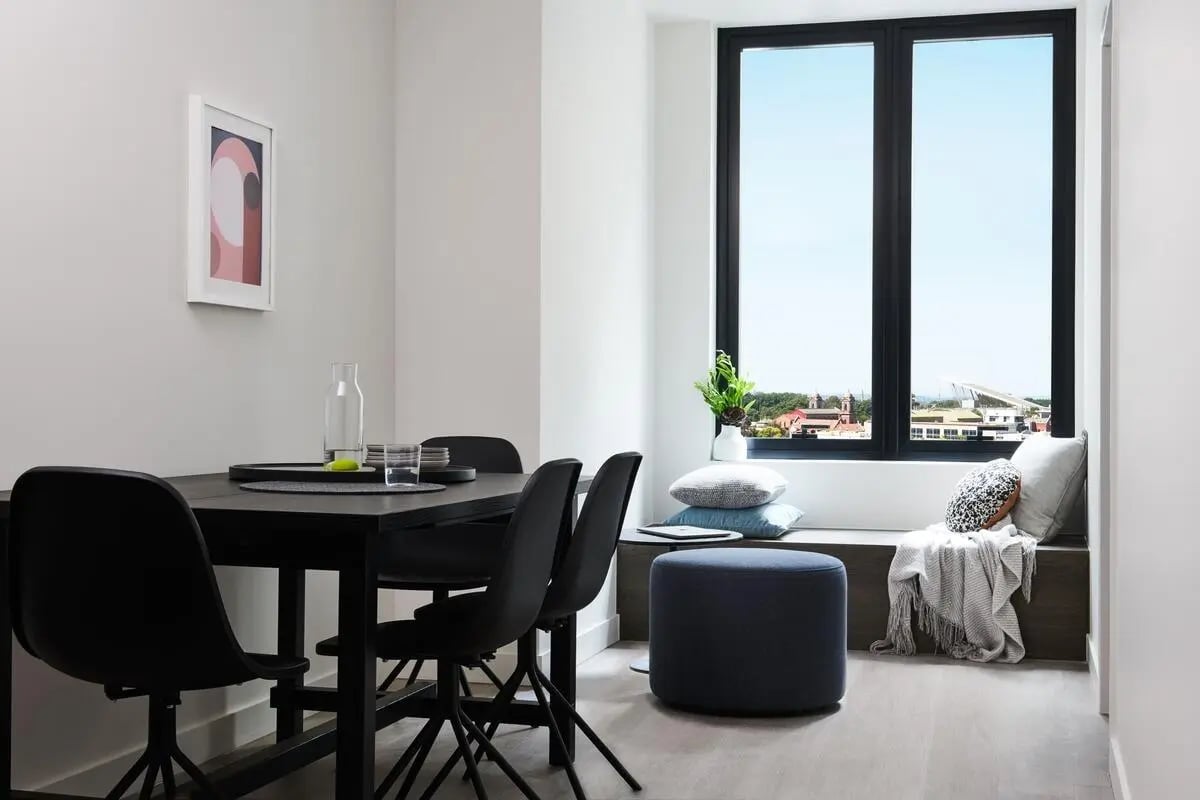 Black dining table chairs artwork window seating dining area at Scape Cornell Place in Melbourne Student Accommodation