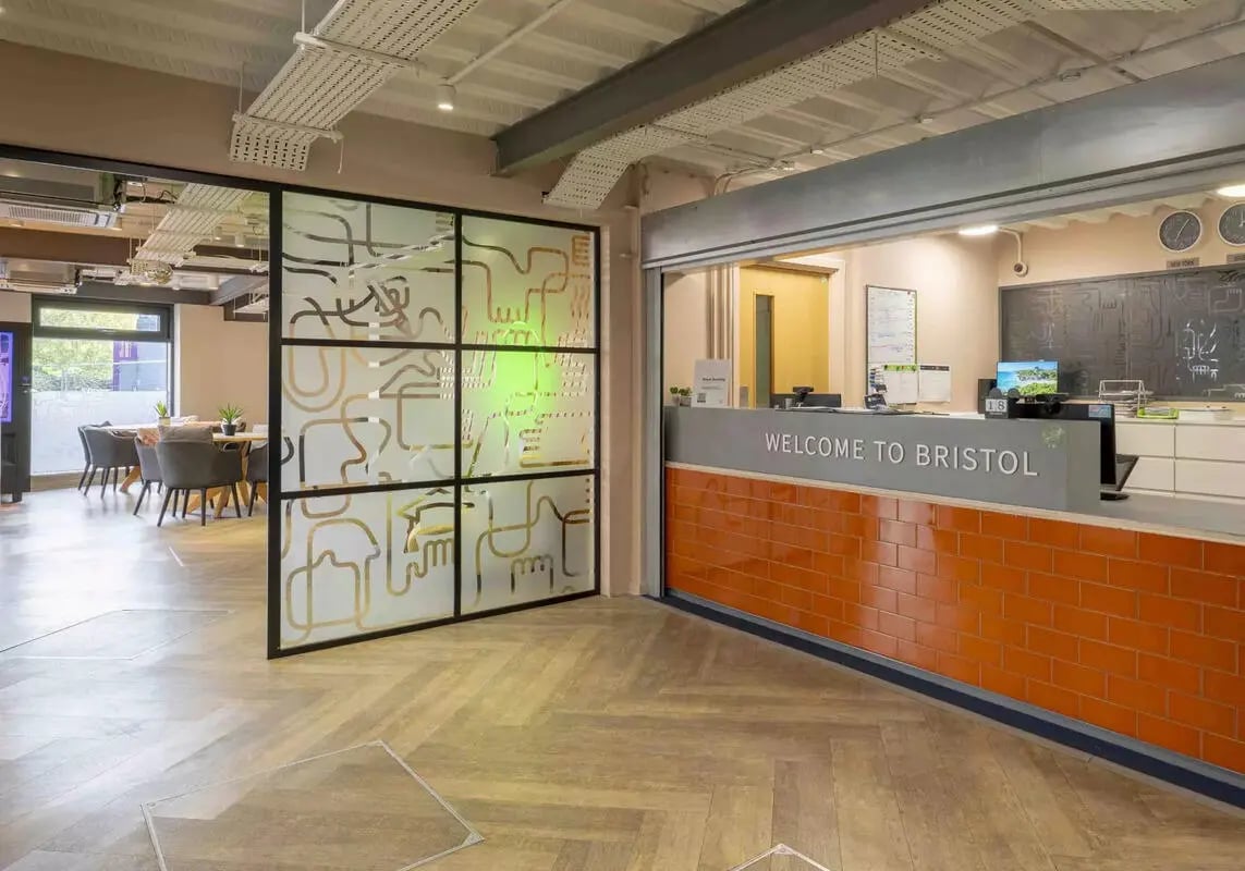 Reception desk with welcome sign and seating area at iQ Bristol in Bristol Student Accommodation