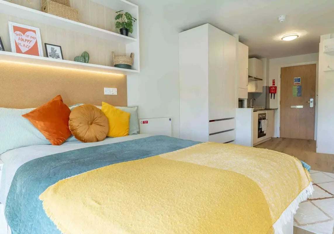 Bed with pillows wardrobe kitchen and door bedroom at iQ Bristol in Bristol Student Accommodation