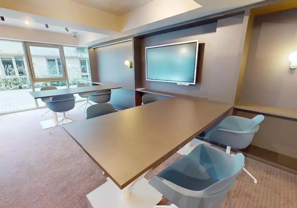 Large tables chairs and wall mounted screen communal area at iQ Hoxton in London Student Accommodation
