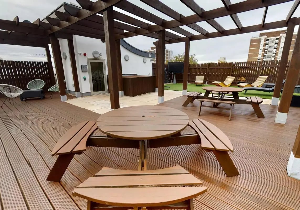 Outdoor seating area with picnic tables and chairs exterior at iQ Hoxton in London Student Accommodation