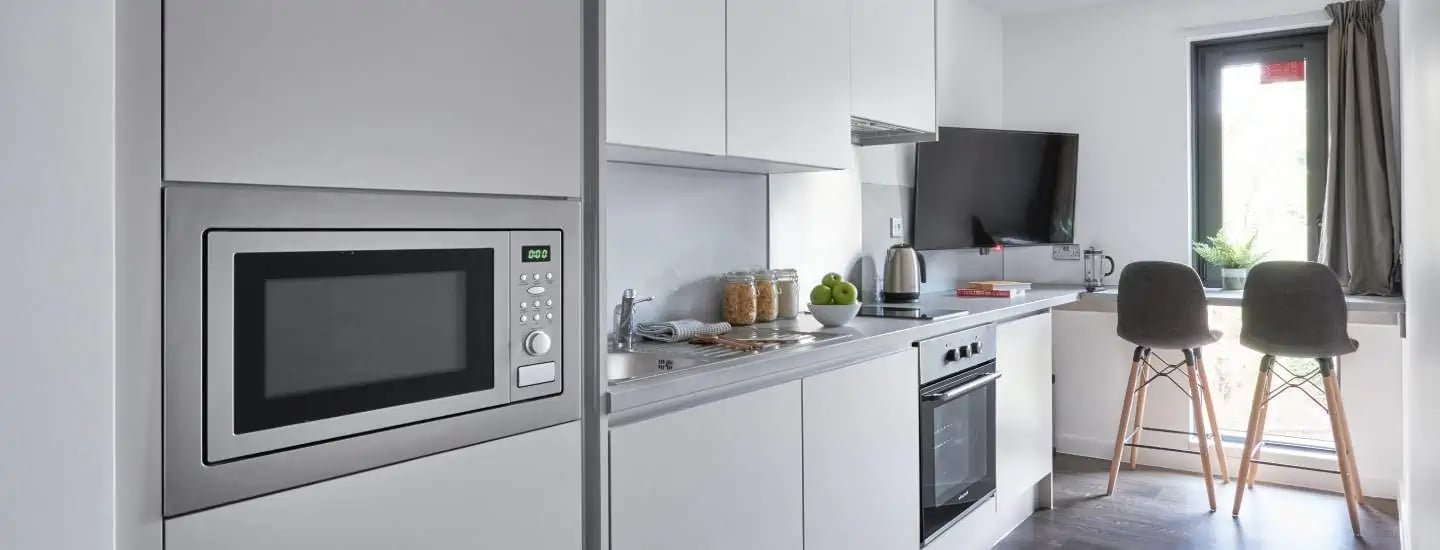 Microwave sink oven television two chairs kitchen at The Glassworks Leicester in Leicester Student Accommodation