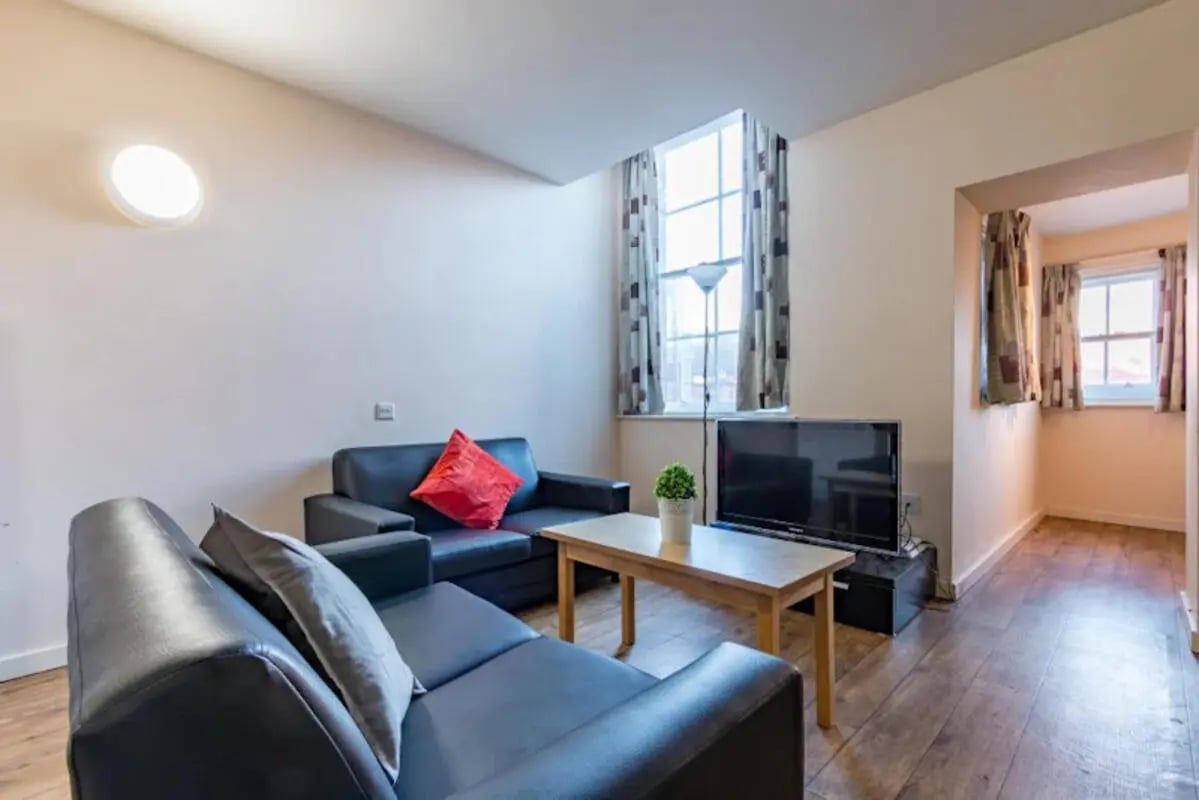 Black sofas coffee table television living room at Chambers 51 in Wolverhampton Student Accommodation