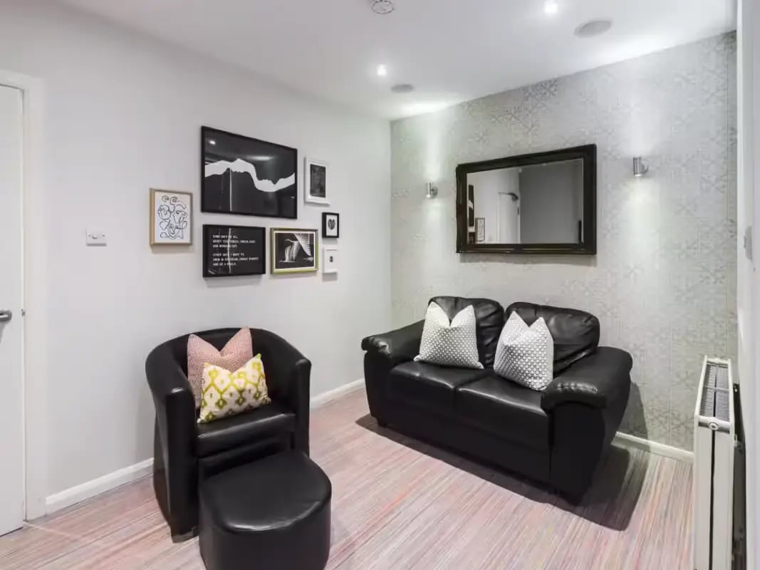 Black sofa armchair framed pictures patterned wallpaper living room at 6 Cauldon Road in Stoke-On-Trent Student Accommodation