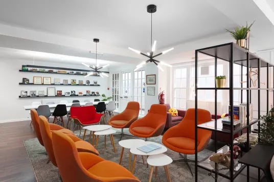 Orange chairs white tables modern light living room at Louise House in London Student Accommodation