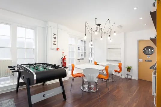 Foosball table round tables orange chairs playing area at Louise House in London Student Accommodation