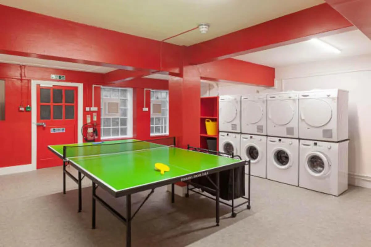 Ping pong table and stacked washers and dryers common area at Louise House in London Student Accommodation