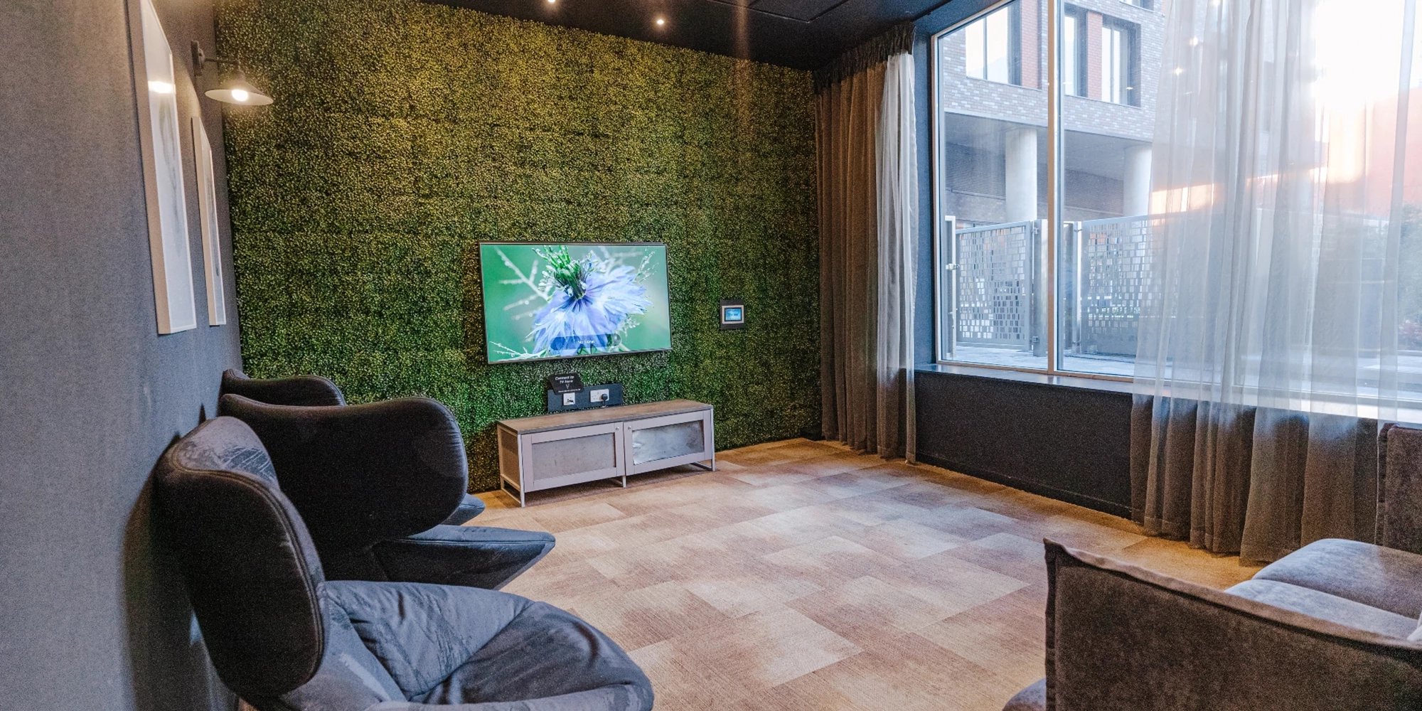 Black chairs TV on green wall lounge area at Canvas Coventry City Point in Coventry Student Accommodation