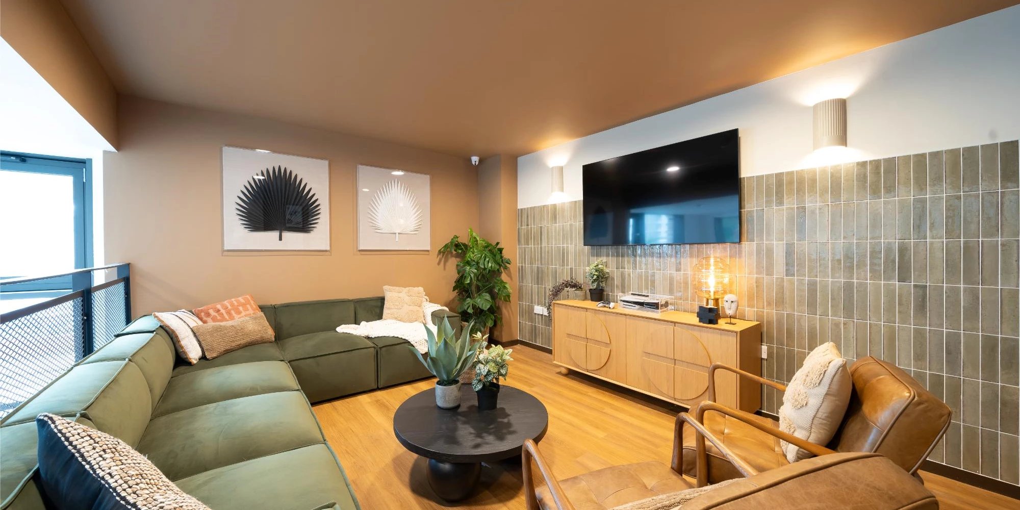 Green sectional sofa television and lounge chairs living room at Canvas Glasgow in Glasgow Student Accommodation