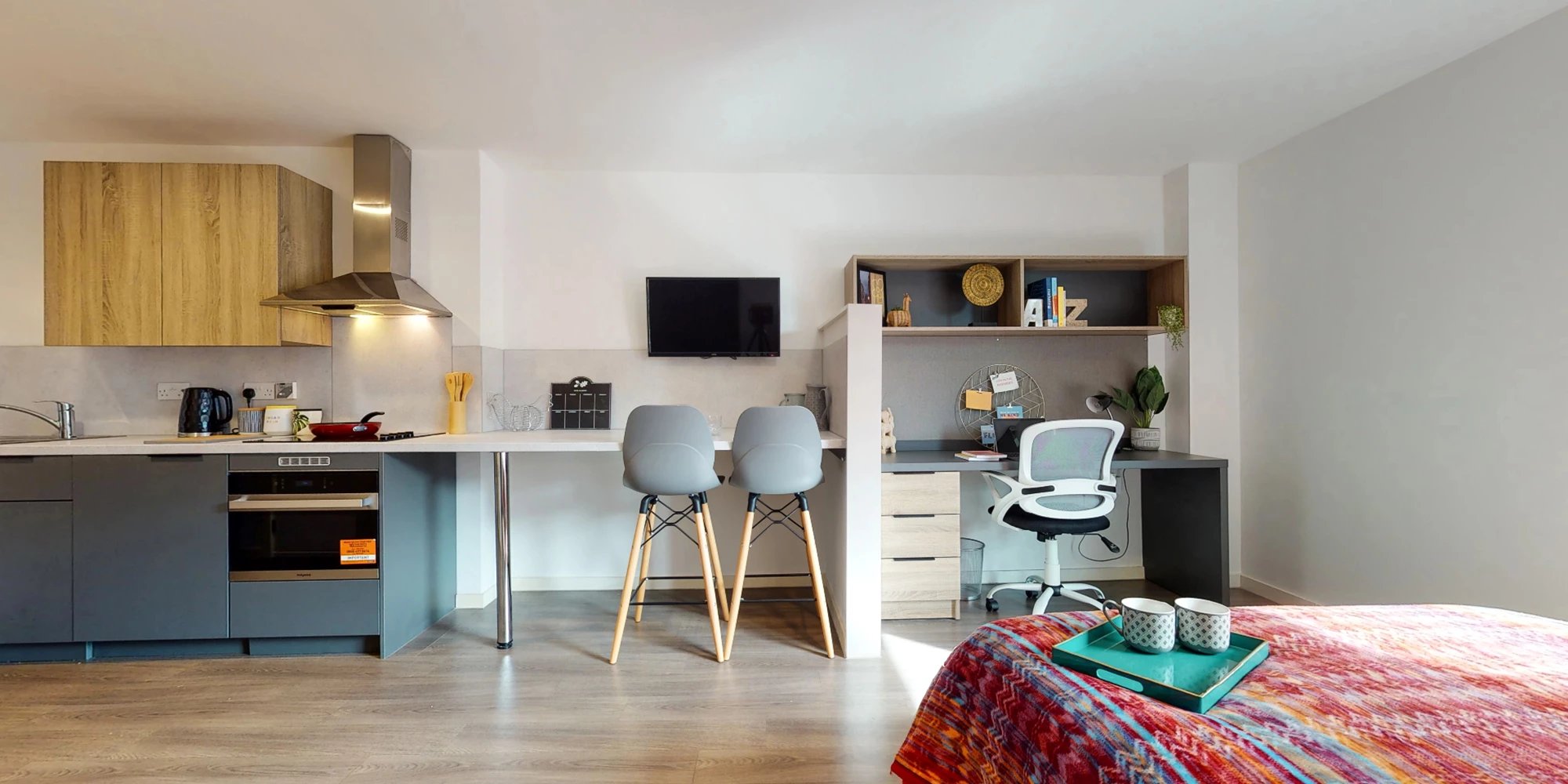Kitchen island with chairs study desk and bed living room at Canvas Glasgow in Glasgow Student Accommodation