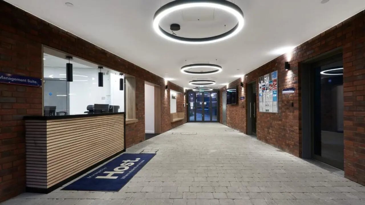 Reception desk with circular lights and brick walls lobby at 41 Castle Street in Leicester Student Accommodation
