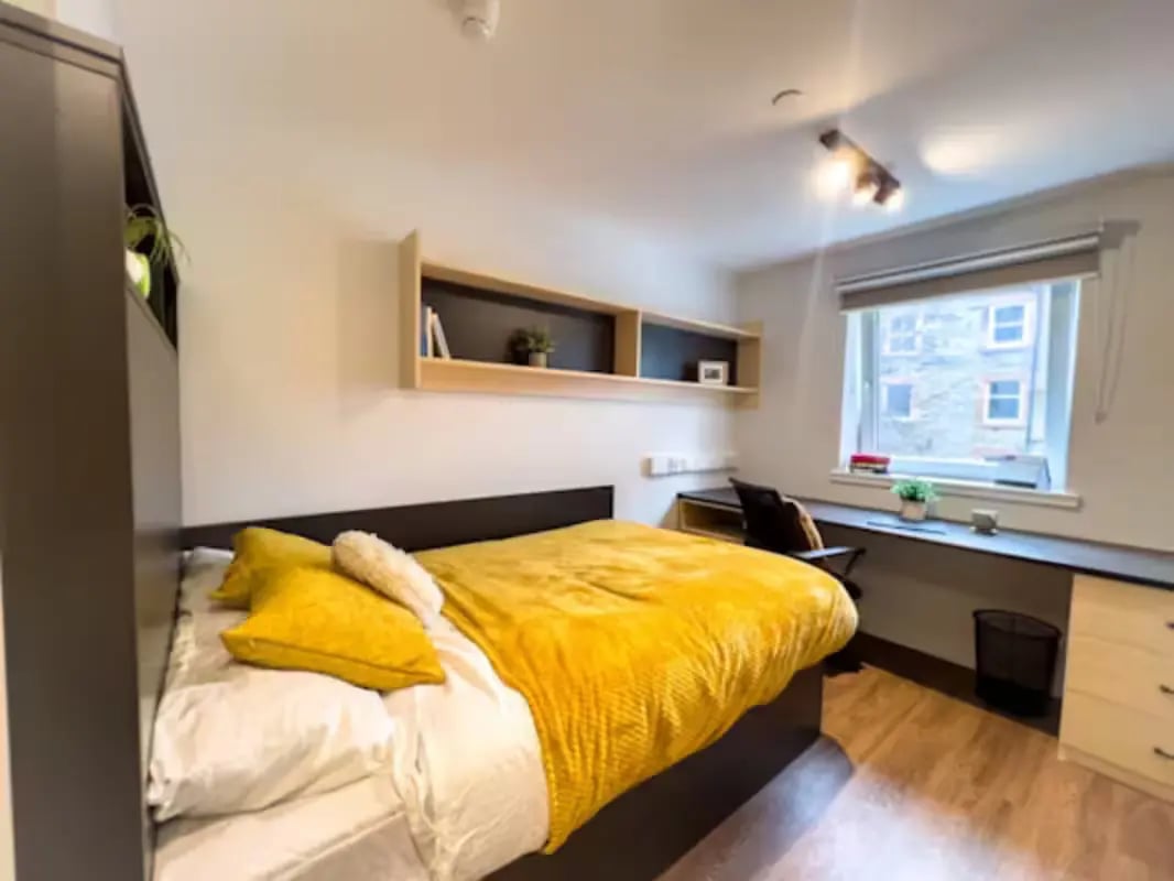 Bed with yellow blankets desk with chair bedroom at Portsburgh Court in Edinburgh Student Accommodation