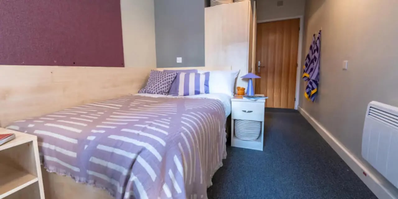 Bed with purple accents wooden wardrobe door towel Bedroom at The Heights in Birmingham Student Accommodation