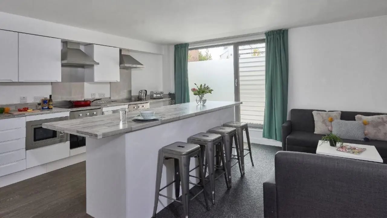 Modern kitchen island with stools and sofa living room. at Selly Oak Apartments in Birmingham Student Accommodation