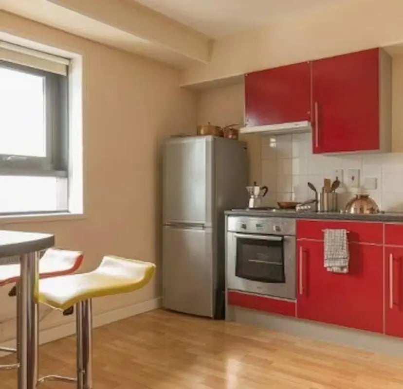 Red cabinets fridge oven stools kitchen at Newcastle 1 in Newcastle Upon Tyne Student Accommodation