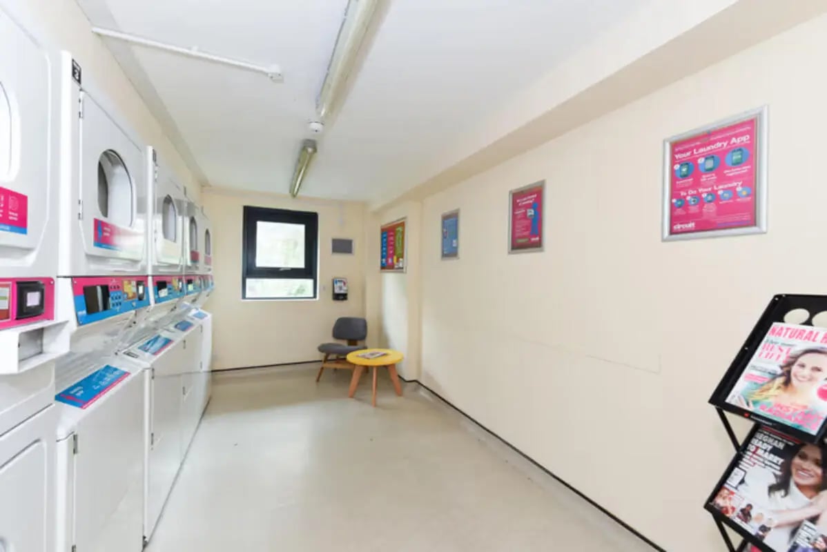 Row of laundry machines and seating area laundry room at Newcastle 1 in Newcastle Upon Tyne Student Accommodation