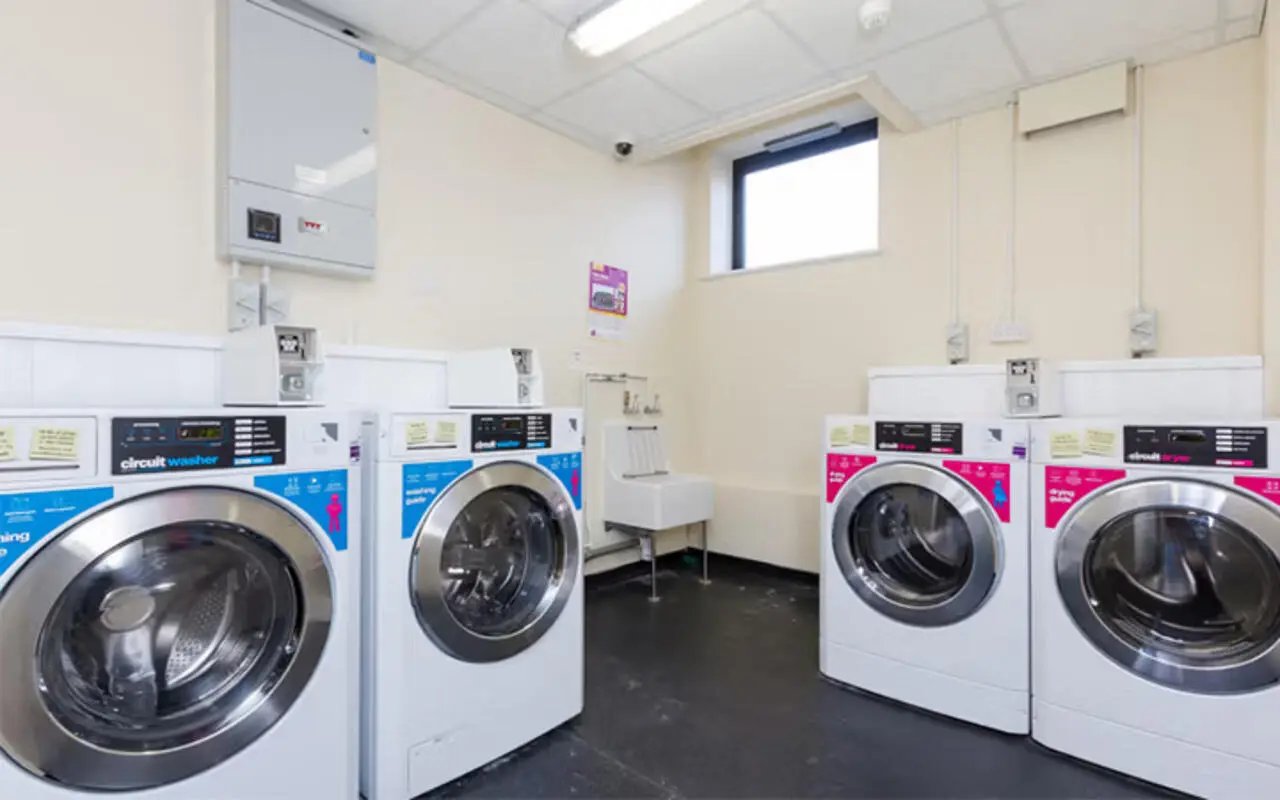 Four washing machines and one sink laundry room at The Hub in London Student Accommodation