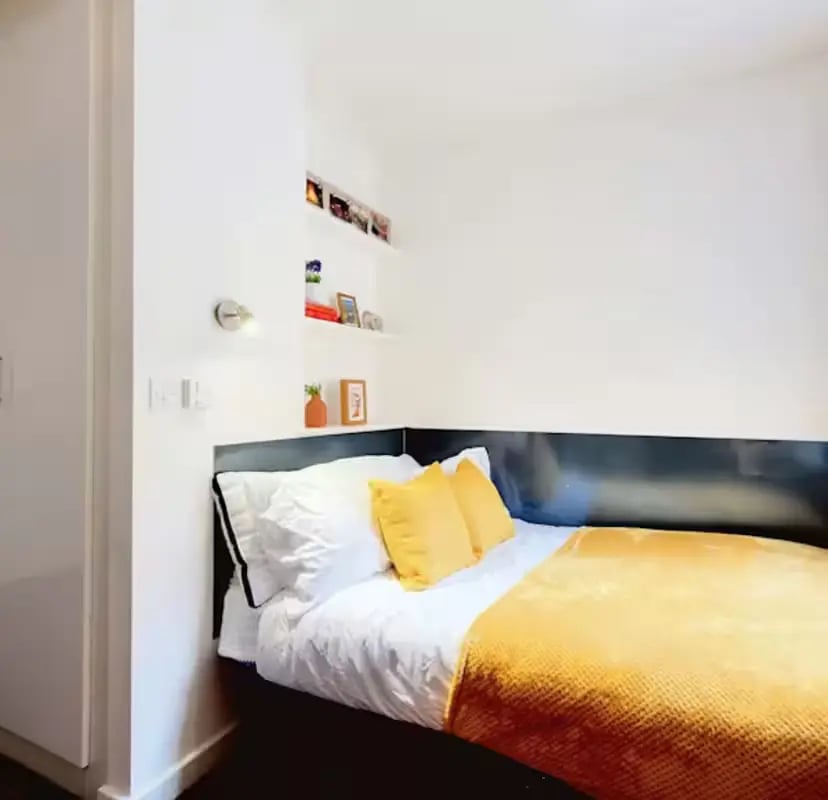 Bed with white linens and yellow pillows bedroom at Newarke Street Leicester in Leicester Student Accommodation