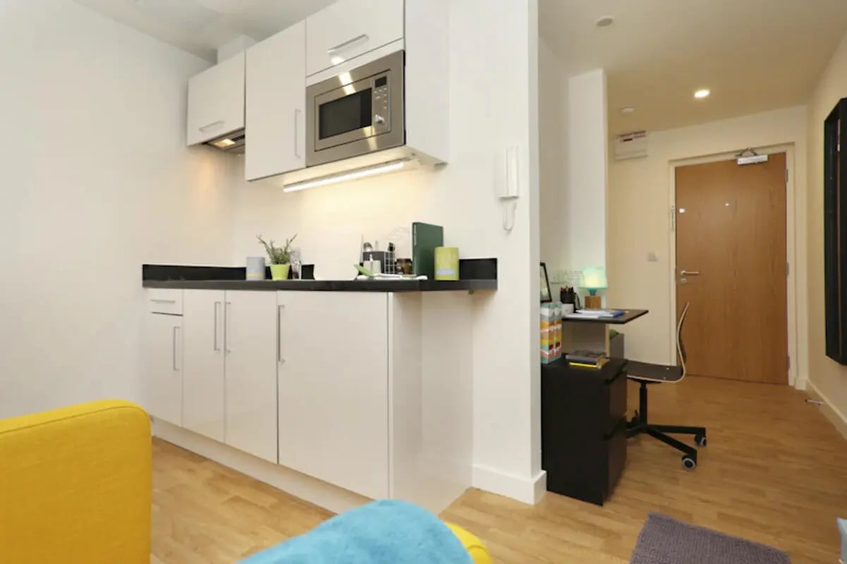White kitchen cabinets microwave sink study desk door studio apartment at Keele House in Newcastle Under Lyme Student Accommodation
