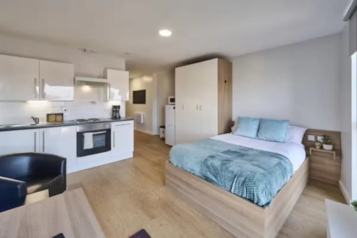 Kitchen and bed with blue bedding studio apartment at The Summit Leicester in Leicester Student Accommodation