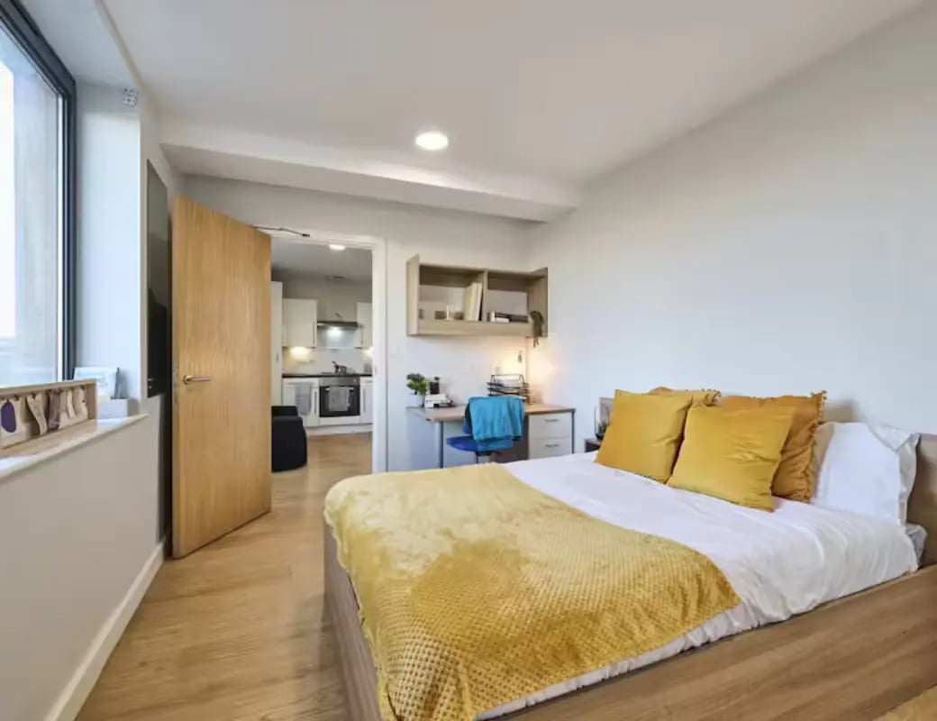 Bed with yellow pillows study area kitchen bedroom at The Summit Leicester in Leicester Student Accommodation