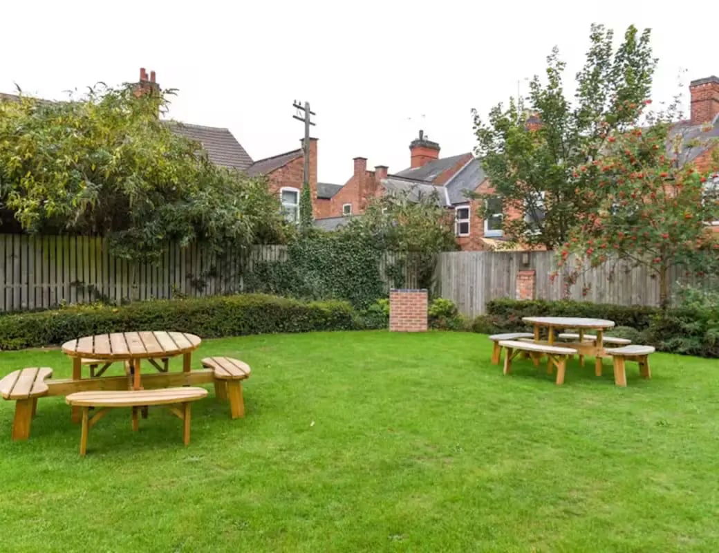 Wooden picnic tables on a green lawn exterior at The Summit Leicester in Leicester Student Accommodation