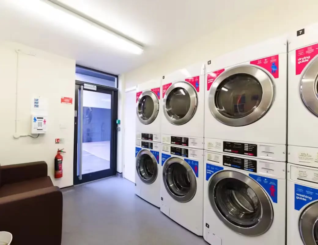 Row of stacked washing and drying machines lounge area Laundry room at The Summit Leicester in Leicester Student Accommodation